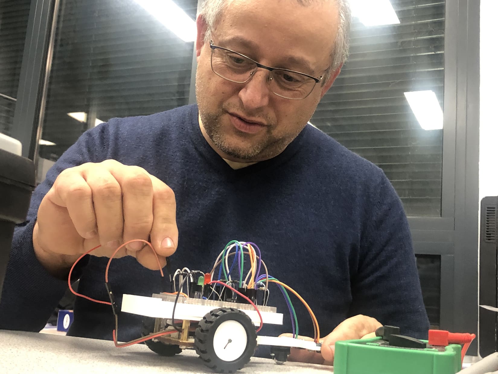 Olivier Lafont, adhérent du Fablab, effectuant quelques branchements sur son robot. Crédit photo GG